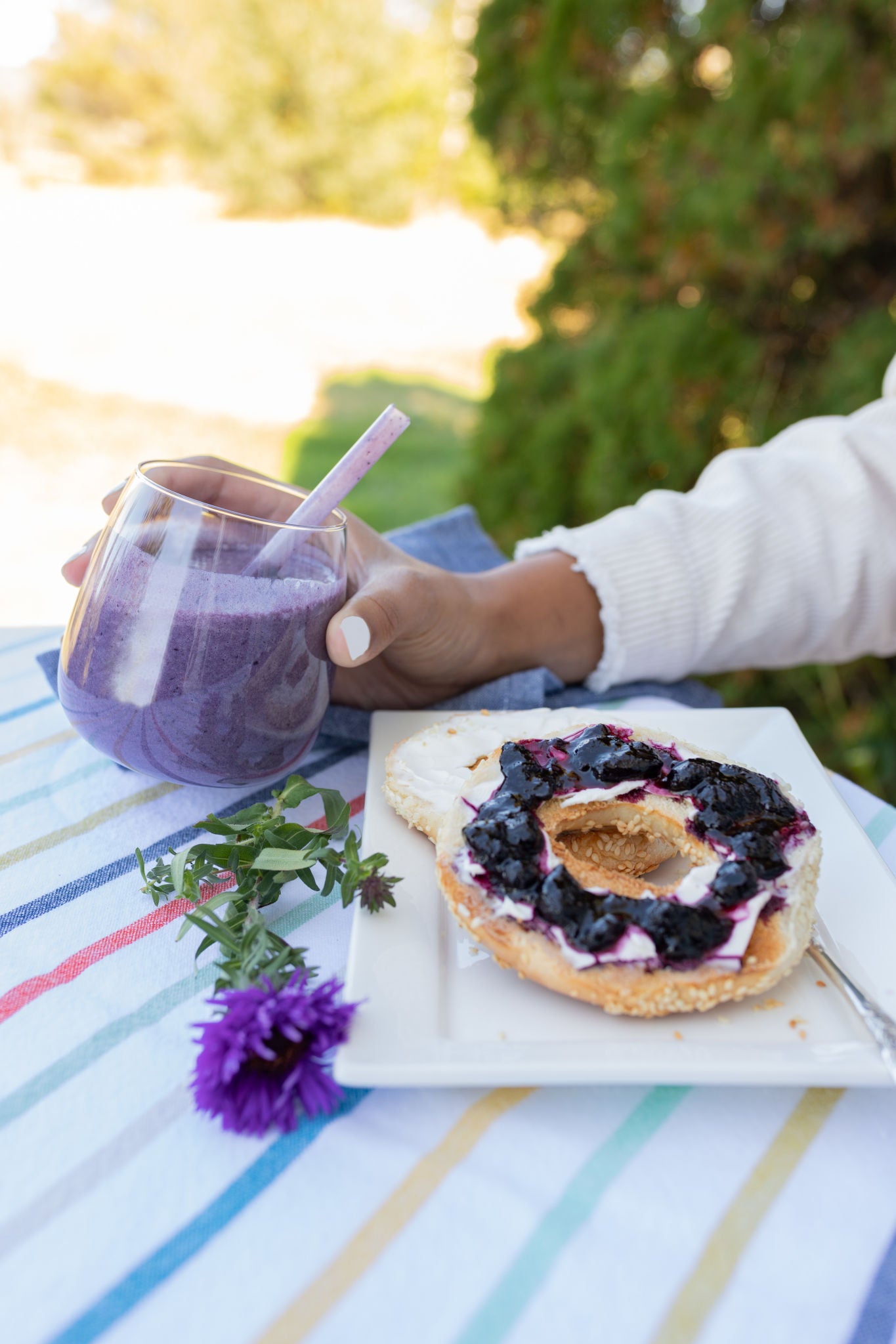 Tablecloth with haskap berry preserve and cream cheese on a bagel, palted, and a glass of haskap berry smoothie