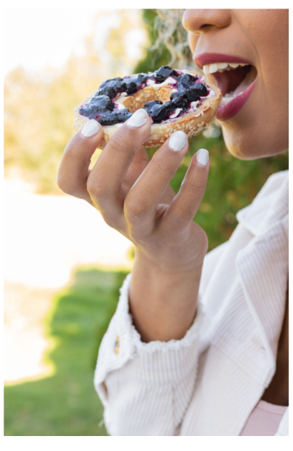 Haskap jam preserve on a bagel with cream cheese being eaten outdoors in Nova Scotia, Canada