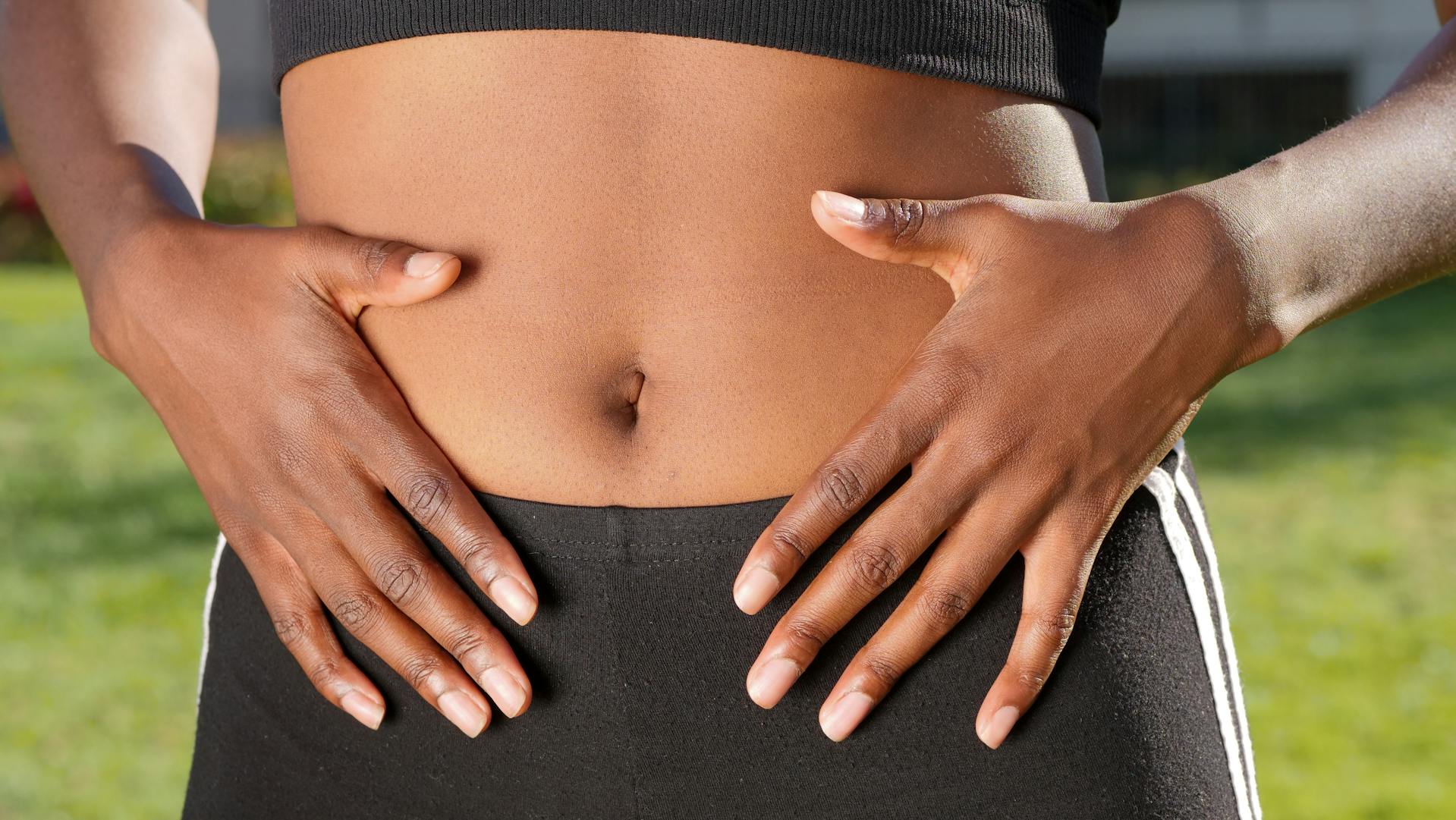 A woman with her hands on her tummy, suggesting digestive distress.